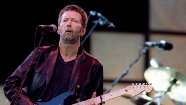 Eric Clapton spielt Gitarre und singt bei einem Konzert.
