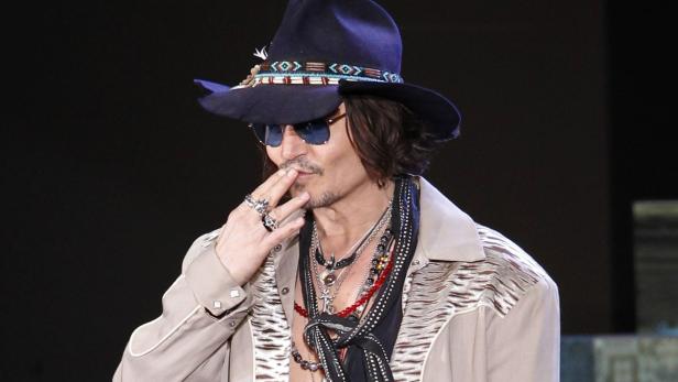 Johnny Depp mit Hut und Sonnenbrille raucht eine Zigarette.