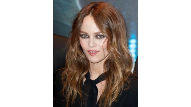 Porträt von Vanessa Paradis mit gewelltem Haar und dunklem Oberteil.