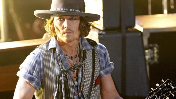 Johnny Depp mit Hut und Gitarre auf der Bühne.