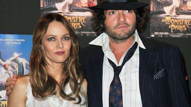 Vanessa Paradis und ein Mann posieren vor einem Filmplakat von „Ein Monster in Paris“.