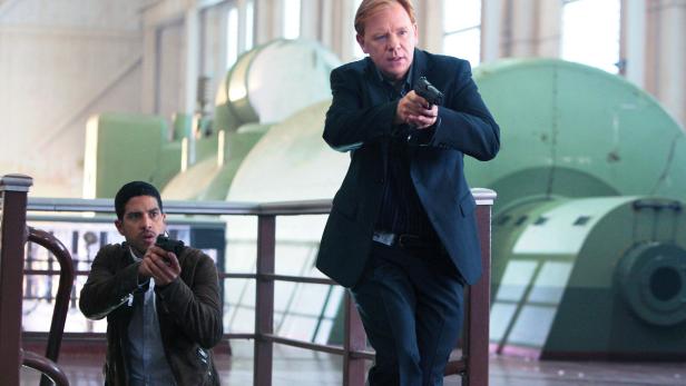 Zwei Männer zielen mit Pistolen in einem Maschinenraum.