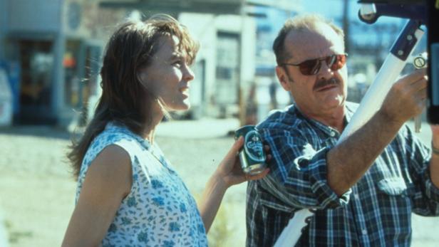 Jack Nicholson am Set von „The Crossing Guard“ mit einer Schauspielerin, die ein Bier hält.