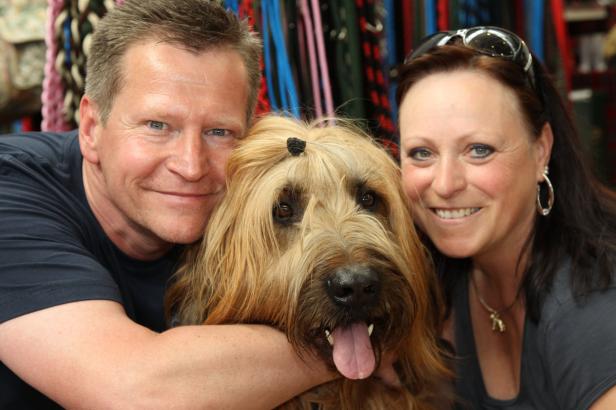 Ein Mann, eine Frau und ein Hund posieren lächelnd für ein Foto.