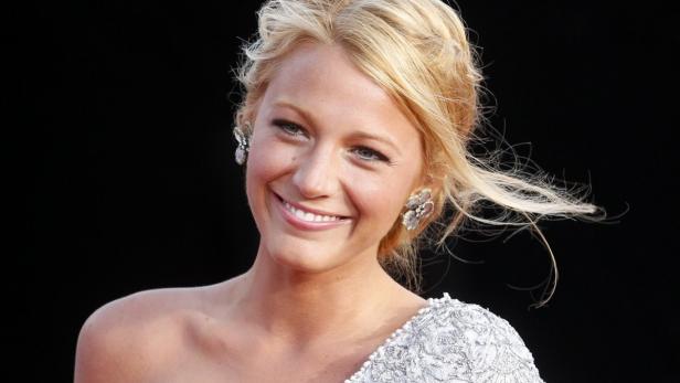 Die lächelnde Schauspielerin Blake Lively mit blonden Haaren und auffälligen Ohrringen.