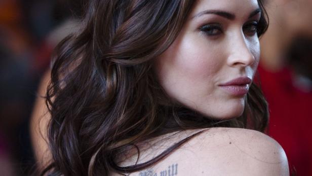 Nahaufnahme von Megan Fox mit gewelltem Haar und einem Tattoo auf der Schulter.