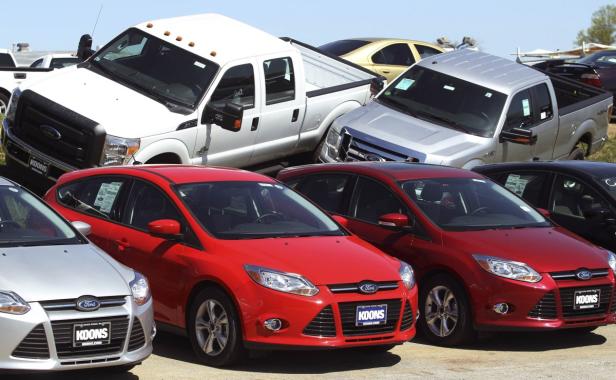 Auf einem Parkplatz stehen mehrere neue Ford-Fahrzeuge, darunter Pickups und PKWs.