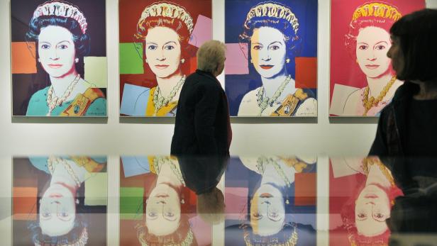 Besucher betrachten Andy Warhols farbenfrohe Porträts von Königin Elisabeth II. in einer Kunstgalerie.