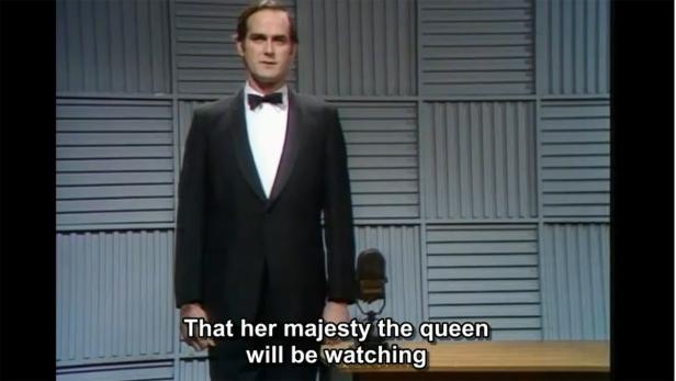 John Cleese in Smoking vor einem grauen Hintergrund.