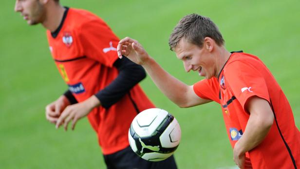 Ein Fußballspieler jongliert den Ball mit der Hand.