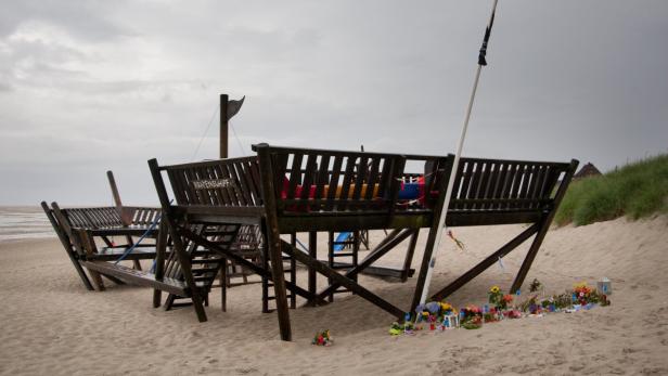 Ein hölzernes Piratenschiff steht am Strand, geschmückt mit Blumen.