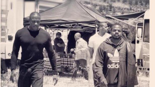 Dr. Dre und Ice Cube stehen in Schwarzweiß vor einem Zelt und Wohnwagen.