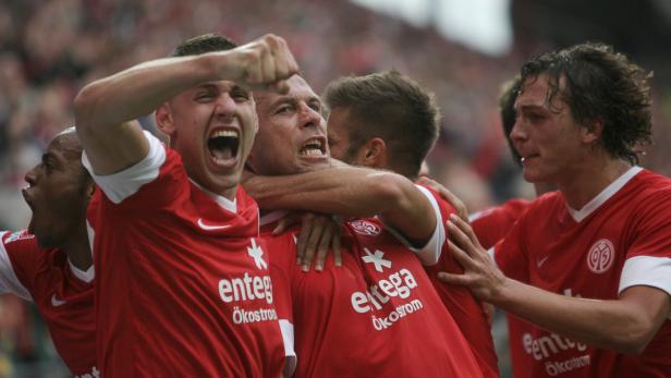 Mehrere Fußballspieler in roten Trikots feiern einen Sieg.