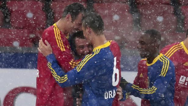 Fußballspieler umarmen sich während eines Schneefalls auf dem Spielfeld.