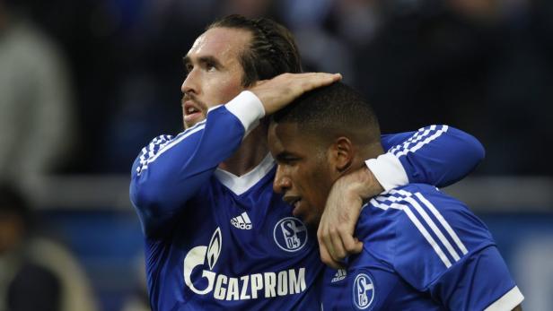 Zwei Fußballspieler des FC Schalke 04 umarmen sich auf dem Spielfeld.