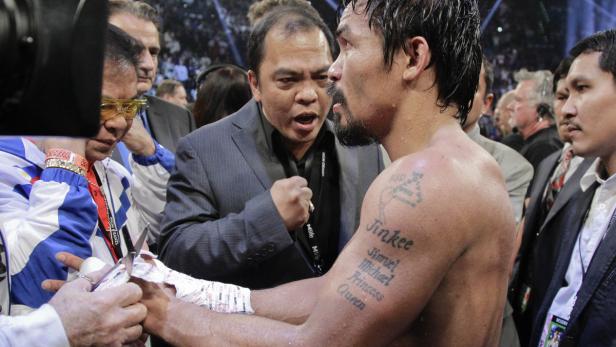 Manny Pacquiaos Hände werden vor einem Boxkampf bandagiert, während sein Trainer ihn anfeuert.