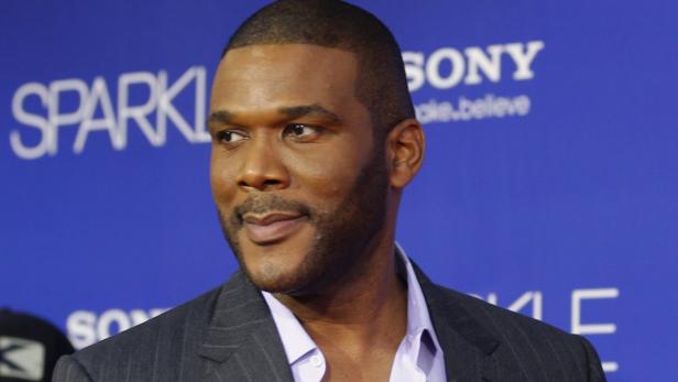 Porträt von Tyler Perry vor einem blauen Hintergrund mit Logos.
