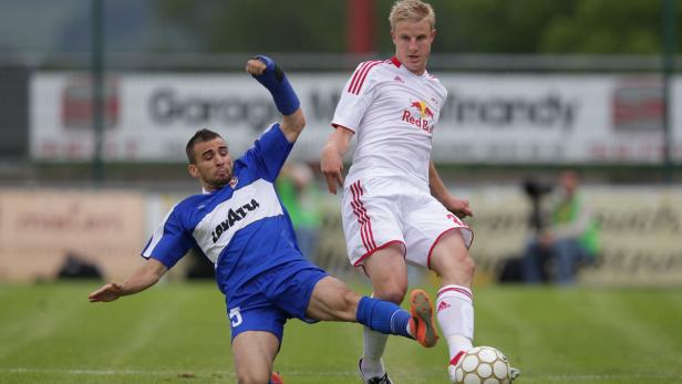 Zwei Fußballspieler kämpfen um den Ball auf dem Spielfeld.
