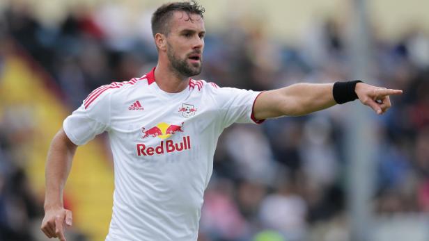 Ein Fußballspieler von Red Bull in weißem Trikot zeigt mit dem Finger nach rechts.