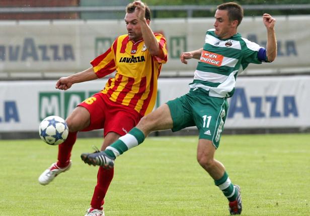 Zwei Fußballspieler kämpfen um den Ball auf dem Rasen.