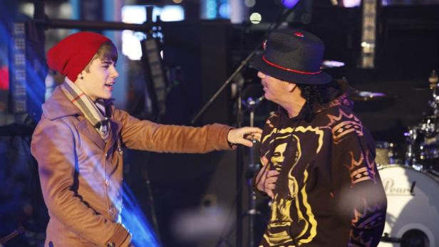 Justin Bieber und Carlos Santana unterhalten sich auf einer Bühne.