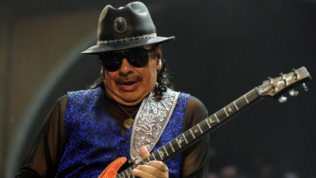 Carlos Santana spielt Gitarre mit Hut und Sonnenbrille.