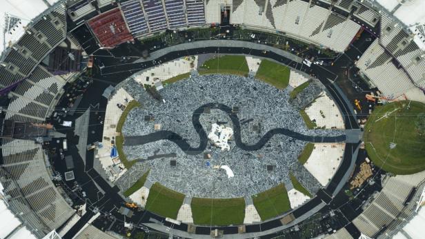 Luftaufnahme eines Stadions mit einer Installation aus Metallschrott und Rasenflächen.