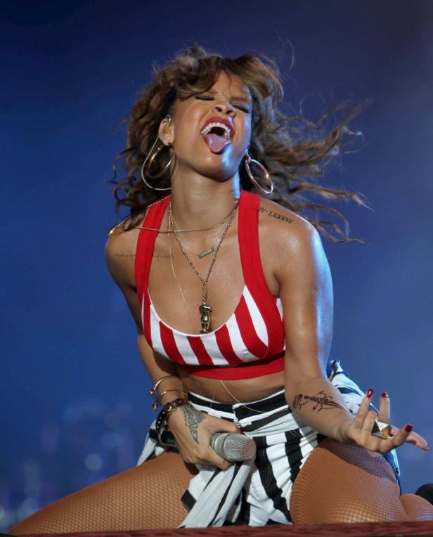 Rihanna tritt in einem rot-weiß gestreiften Top und einem schwarz-weiß gestreiften Rock auf einer Bühne auf.