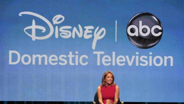 Katie Couric sitzt vor einer Leinwand mit den Logos von Disney und ABC.