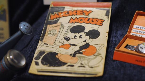 Ein altes Mickey Mouse Comicbuch liegt neben einer Mickey Mouse Armbanduhr in ihrer Originalverpackung.