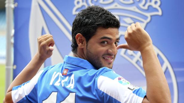 Ein Fußballspieler im blauen Trikot mit der Aufschrift „Vera“ lächelt in die Kamera.