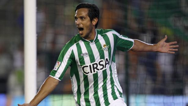 Ein Fußballspieler im grün-weiß gestreiften Trikot jubelt mit geöffnetem Mund und erhobenen Armen.