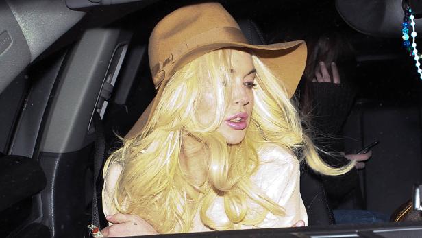 Lindsay Lohan sitzt mit Hut im Auto.