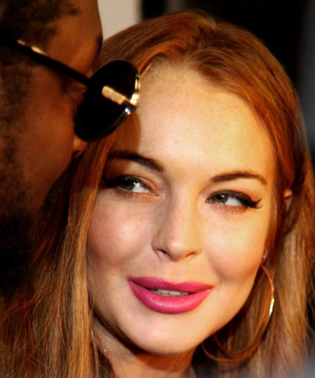 Ein Porträt von Lindsay Lohan mit pinkfarbenem Lippenstift und goldenen Ohrringen.