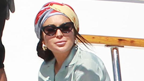 Eine Frau mit Sonnenbrille und Turban an Bord einer Yacht.