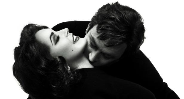 Ein Mann küsst den Hals einer Frau in einer Schwarzweißaufnahme.