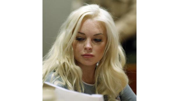 Lindsay Lohan blickt auf ein Dokument.