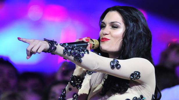 Jessie J singt in einem mit Schmucksteinen verzierten Kleid und zeigt mit dem Finger nach links.
