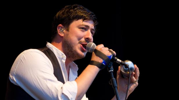 Ein Mann mit Mikrofon singt auf einer Bühne.