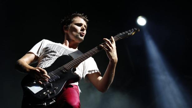 Ein Mann spielt unter einem Scheinwerfer Gitarre.