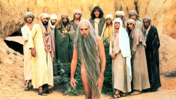 Eine Gruppe von Menschen in biblischer Kleidung steht in einer Wüstenlandschaft.