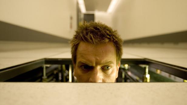 Ein Mann blickt grimmig durch eine Öffnung.