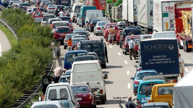 Stau auf einer Autobahn mit vielen Autos und einigen Personen außerhalb ihrer Fahrzeuge.