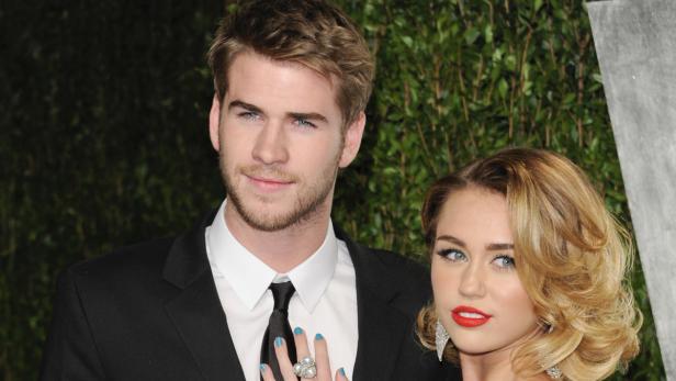 Liam Hemsworth und Miley Cyrus posieren zusammen auf einem roten Teppich.
