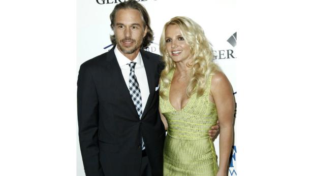 Britney Spears posiert mit einem Mann im Anzug auf einem Event.