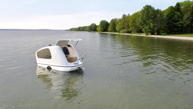 Ein kleines, weißes Hausboot liegt auf einem ruhigen See.