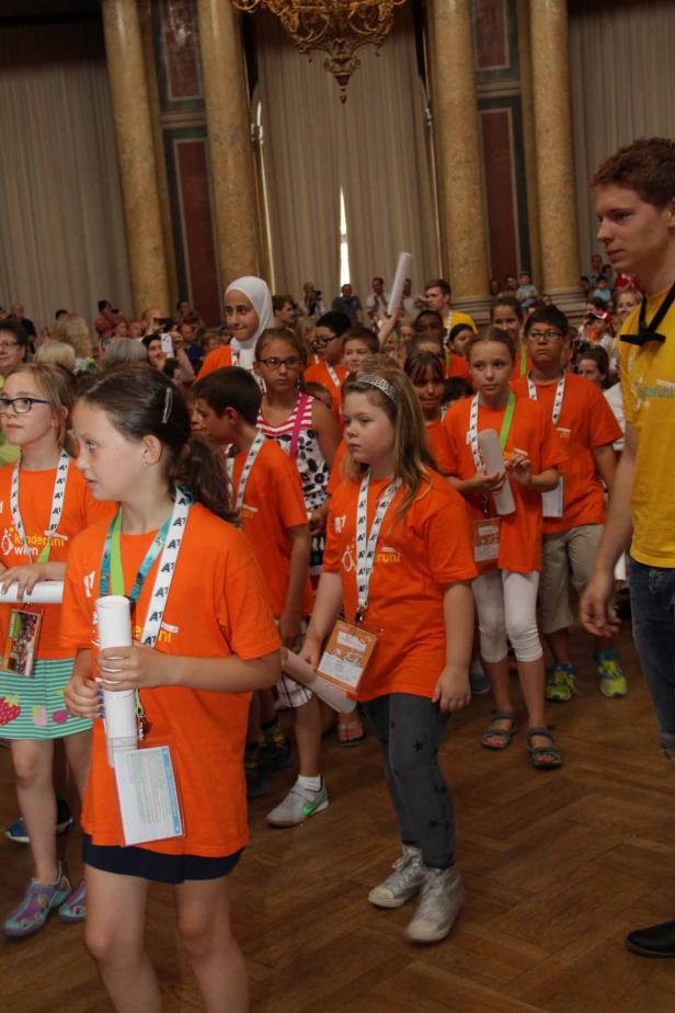 Eine Gruppe Kinder in orangefarbenen T-Shirts steht in einer Halle.