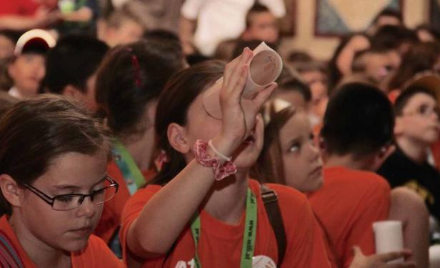 Eine Gruppe von Kindern schaut durch Papierrollen in die Ferne.