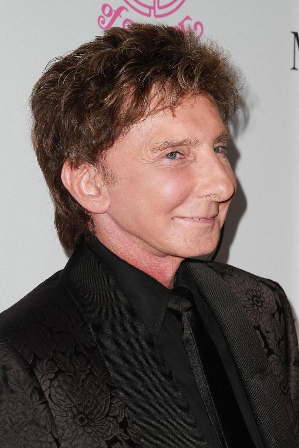 Barry Manilow trägt einen schwarzen Anzug mit Blumenmuster.