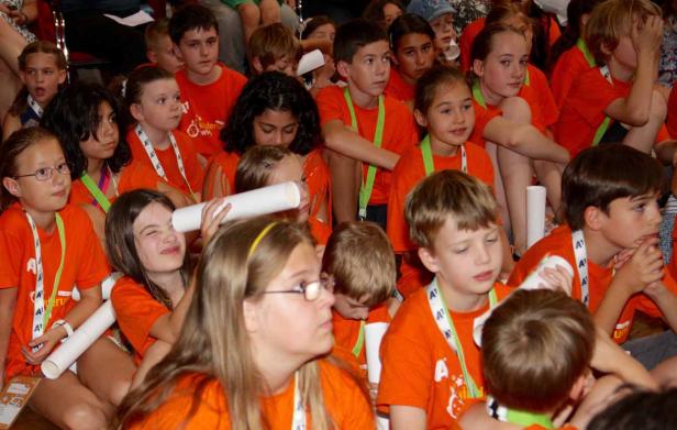 Eine Gruppe Kinder in orangefarbenen T-Shirts sitzt zusammen.